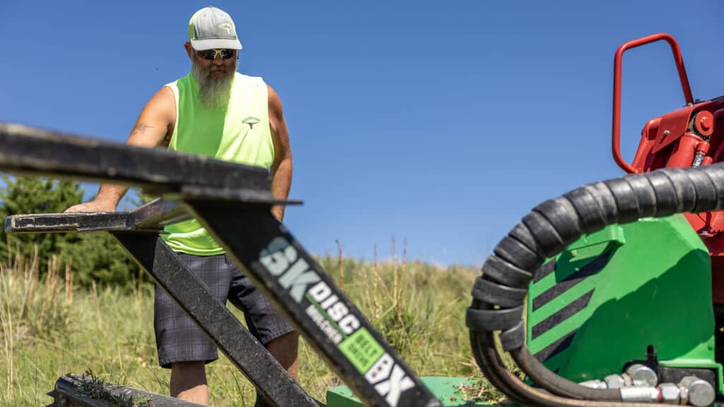 man looking at skid steer disc mulcher belt drive