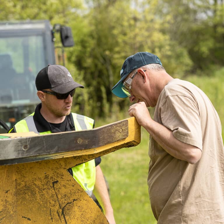 two guys looking at an excavator brush cutter