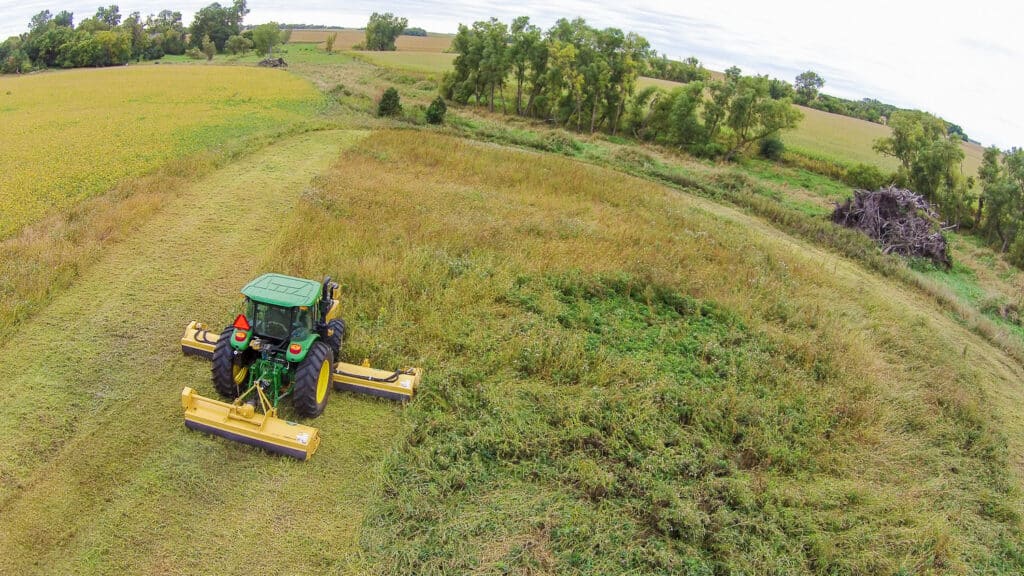 tractor with traditional triple flail on the back mowing grass