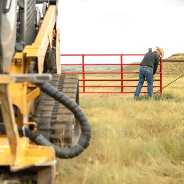 a guy locking up the gate to a pasture