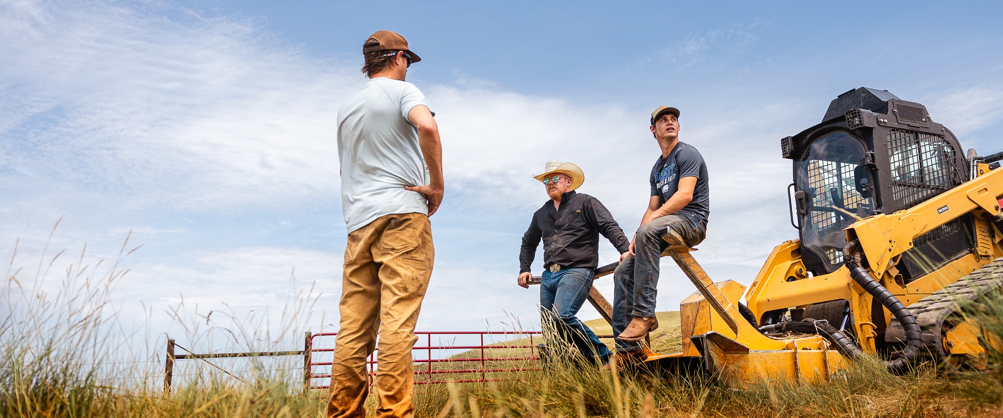 three people around a skid steer talking