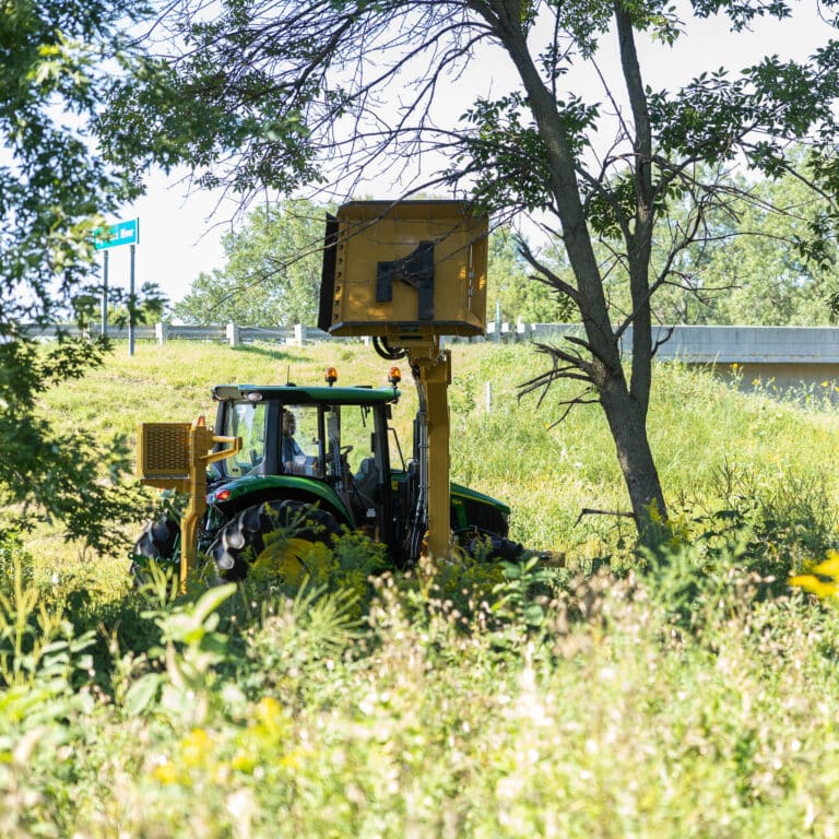 tractor with a mid mount boom rotary mower attached