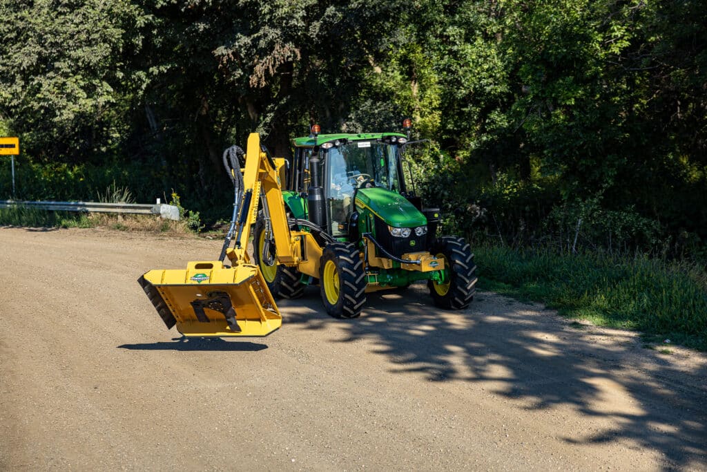 tractor with boom rotary cutting a tree