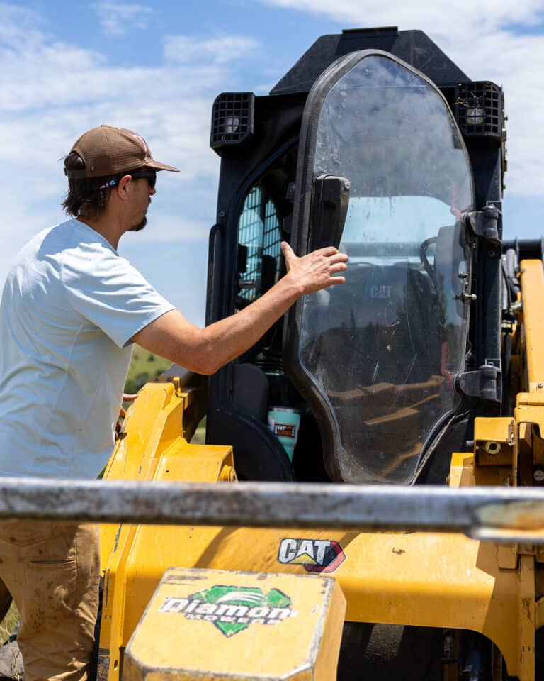 Guy opening polycarb safety door on a skid steer.